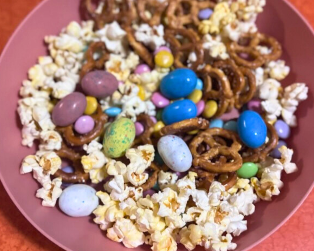 Ingredients for Easter snack mix including popcorn, Peeps, mini Oreos, pastel M&Ms, and Robin Eggs candy